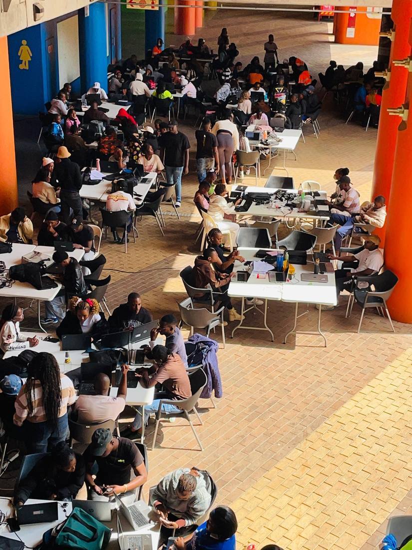 Rural youth and women collaborating in a busy innovation hub workspace.